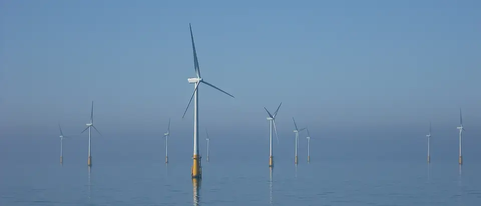 Offshore wind turbines standing in a calm, misty sea off Walney Island in the Irish Sea.